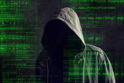A faceless hacker in a hoodie is surrounded by green computer code.